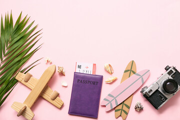 Composition with passport, photo camera, beach accessories and palm leaf on pink background