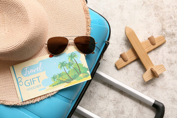 Suitcase with beach accessories, travel gift voucher and wooden plane on grunge background, closeup