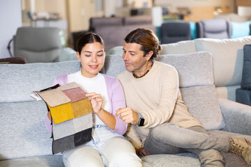 Couple holding fabric swatches and choosing the color for upholstery