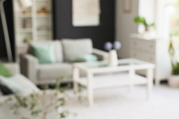 Blurred view of modern living room with grey sofa and glass coffee table