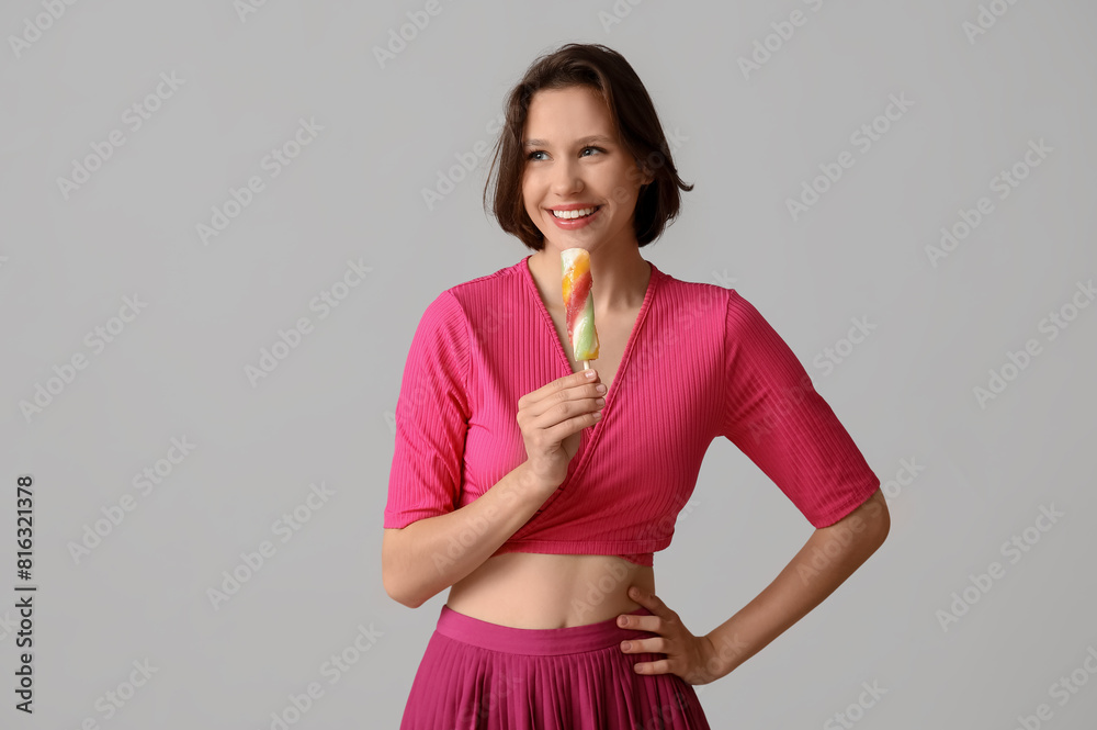 Sticker Beautiful young woman with sweet ice-cream on grey background