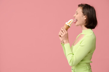 Beautiful young woman eating sweet ice-cream in waffle cone on pink background