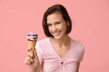 Happy young woman with sweet ice-cream in waffle cone on pink background