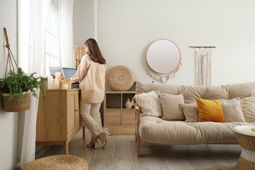 Young woman with record player on commode in cozy living room, back view