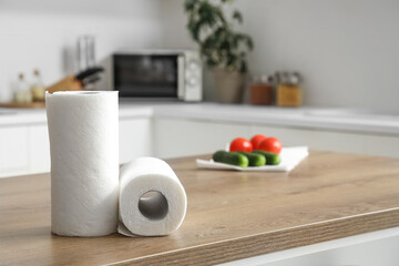 Rolls of paper towels and vegetables on table in kitchen, closeup