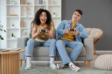 Happy young couple playing video games on sofa at home