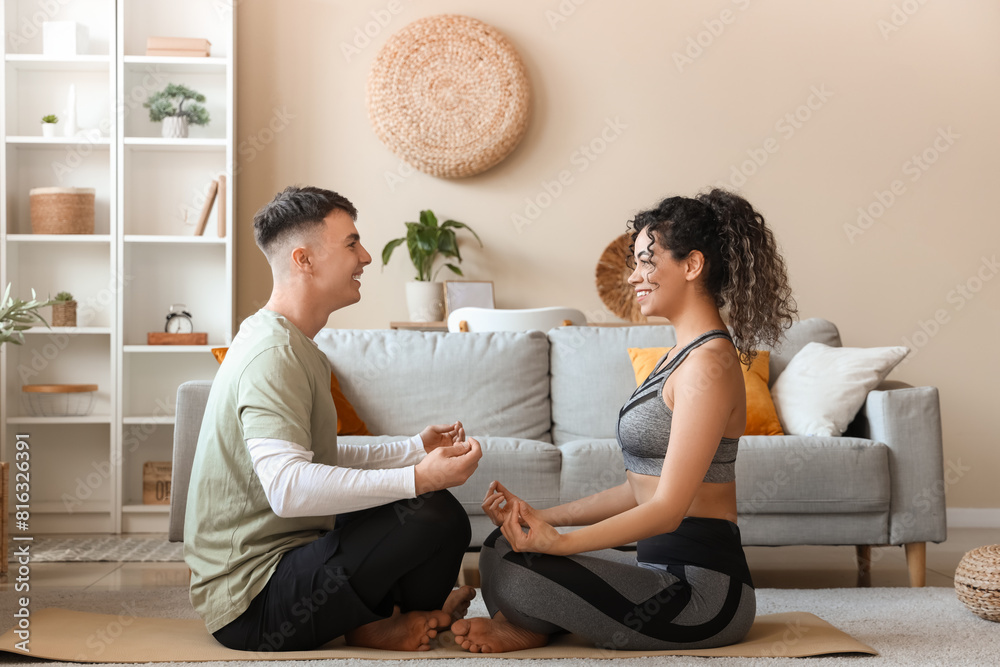 Poster Happy sporty young couple sitting at home