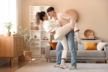 Happy young beautiful couple dancing at home