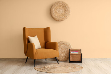 Brown armchair with wicker poufs and magazine near beige wall
