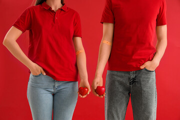 Blood donors with applied patches and grip balls on red background, closeup