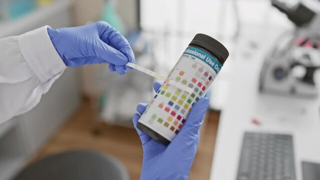 A healthcare professional in a lab uses a dipstick for urine analysis testing, indicating medical diagnostics in an indoor setting.