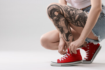 Woman with cool tattoos on grey background, closeup. Space for text