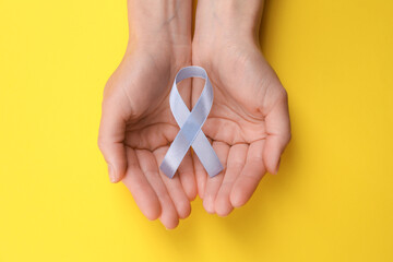 International Psoriasis Day. Woman with light blue ribbon as symbol of support on yellow...