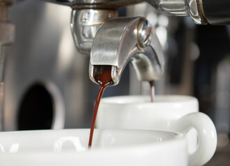 A closeup of a shining espresso coffee machine filling a mug