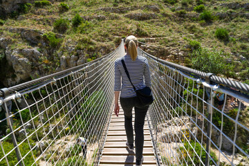 Woman walking across suspension bridge near Matera Italy