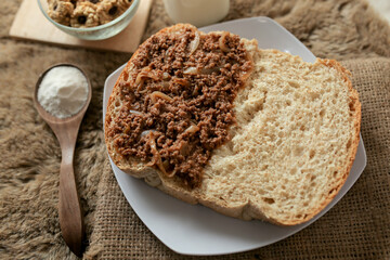 Bread with minced beef and union on a table. With white milk and snack for breakfast	
