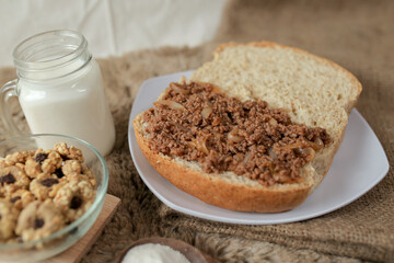 Bread with minced beef and union on a table. With white milk and snack for breakfast	
