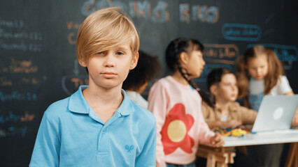 Smart boy looking at camera while diverse friend working or learning engineering code or prompt in...