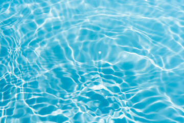 Blue water with ripples on the surface. Defocus blurred transparent blue colored clear calm water surface texture with splashes and bubbles. Water waves with shining pattern texture background.