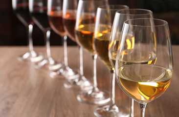 Different tasty wines in glasses on wooden table, space for text