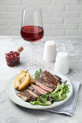 Delicious roasted beef meat, caramelized pear and greens served on light table