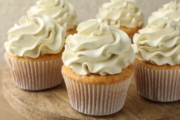Tasty vanilla cupcakes with cream on table, closeup