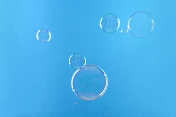Beautiful transparent soap bubbles on light blue background