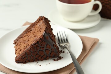 Piece of delicious chocolate truffle cake and fork on white table, closeup