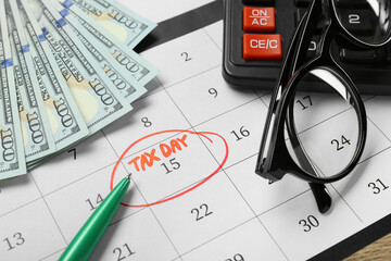 Calendar with date reminder about tax day, pen, glasses, money and calculator, closeup