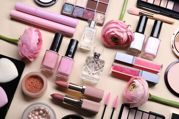Flat lay composition with different makeup products and beautiful spring flowers on beige background