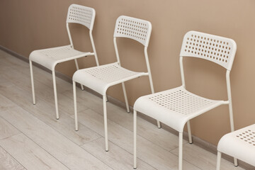 Many chairs near beige wall in waiting area indoors