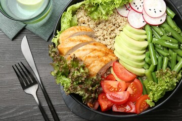 Healthy meal. Tasty products in bowl and cutlery on black wooden table, flat lay