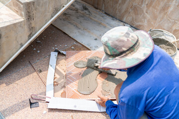 Worker tile mason spreading adhesive on tile