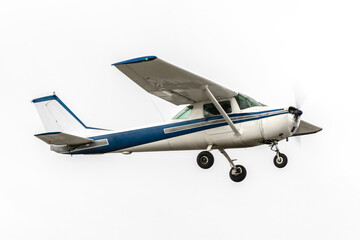 Blue and white light aircraft in flight. Propellor driven high wing aircraft used for recreation and flight training. Classic general aviation airplane isolated