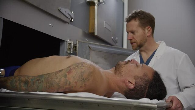 Medical examiner and corpse of young man in morgue