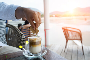 Hand to add sugar or creamer in coffee drink in preparation of the milk coffee of latte and cappuccino art at Cafe shop, business drinking.