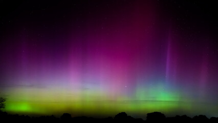 Brilliant colors of Northern Lights in night sky after a rare G5 geomagnetic storm caused the...