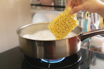 cooking instant noodle with an egg, in the stainless pan