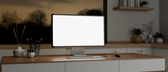 A computer mockup and decor on a wooden desk in a minimalist contemporary room in the evening.