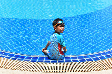 cute boy sit on the swimming pool, happy child