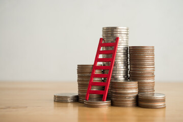 Red ladder and stack coin on wooden table with white wall background copy space. Money management...