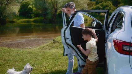 Grandfather and grandson get out of the car, coming to visit the family on a camping trip in nature 