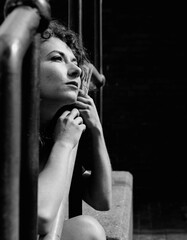 Young woman sitting on stairs and looking away with a dreamy expression.