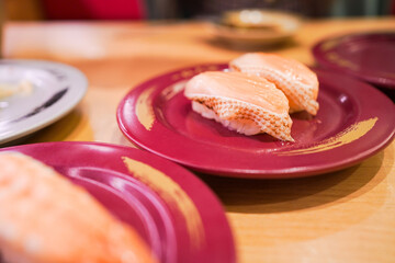 Happy Asian woman eating Sushi at modern Japanese Sushi bar.