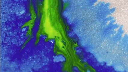 Glitter paint spill. Ink flow. Blur green blue white color shimmering grain texture liquid mix wave motion abstract art background.