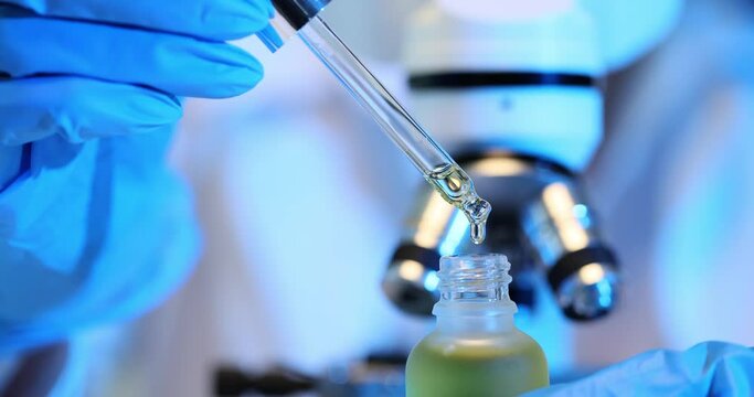 Chemist scientist drips cosmetic oil from pipette into laboratory