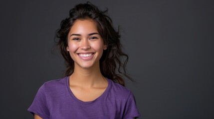 Portrait of beautiful smiling mixed race woman wearing purple tshirt isolated on dark grey...