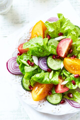 Salad with red and yellow Tomatoes and Pomegranate Seeds on bright wooden Background. Close up.	