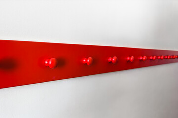 Wooden red hangers hooks on a white wall. Abstract composition, selective focus.