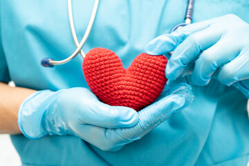 Doctor holding a red heart in hospital ward, healthy strong medical concept.